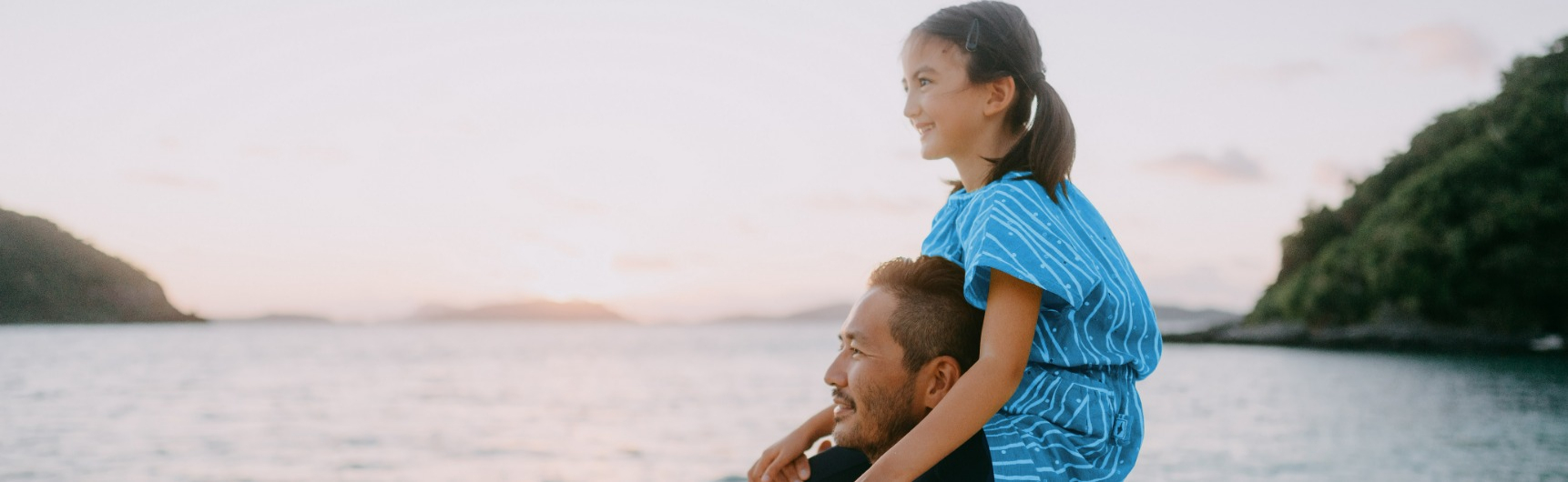 A girl sits on her father's shoulders